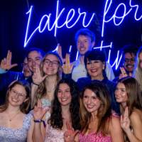 Group of grads gives anchor up sign with Philly in front of Laker for a Lifetime sign